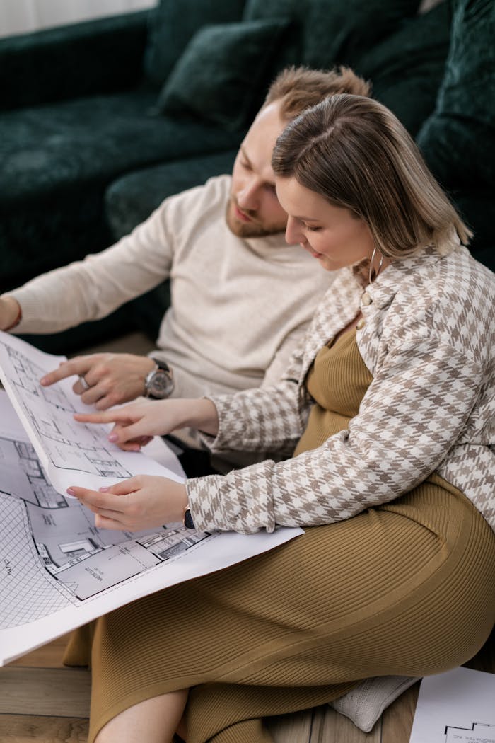 Couple examining architectural blueprints, symbolizing home planning or buying process.